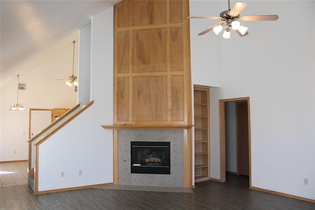 unfurnished living room featuring a ceiling fan, high vaulted ceiling, a tiled fireplace, and wood finished floors