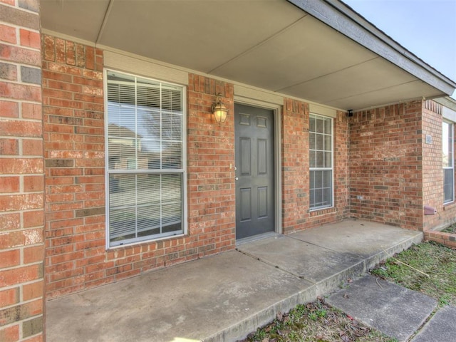 property entrance with brick siding and covered porch