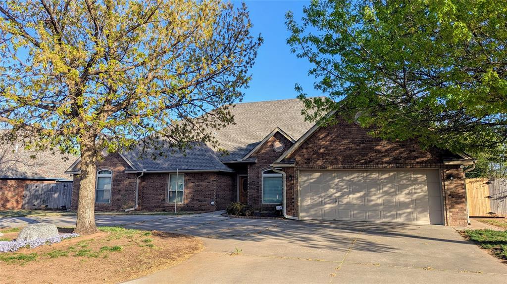 9908 Thompson Ave, Yukon, OK 73099 - view of front facade with brick siding, an attached garage, fence, and concrete driveway