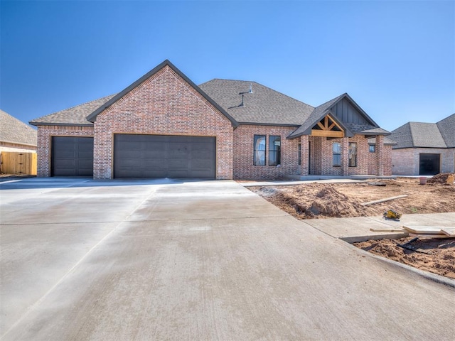 view of front facade featuring a garage, concrete driveway, brick siding, and roof with shingles