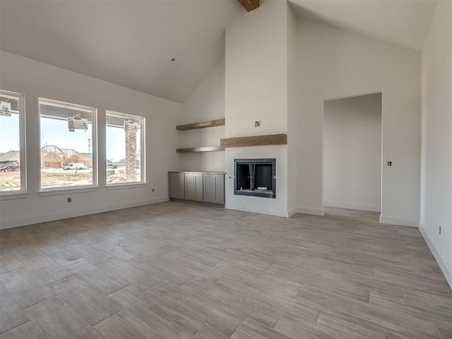 unfurnished living room featuring high vaulted ceiling, a fireplace, light wood-style flooring, and baseboards