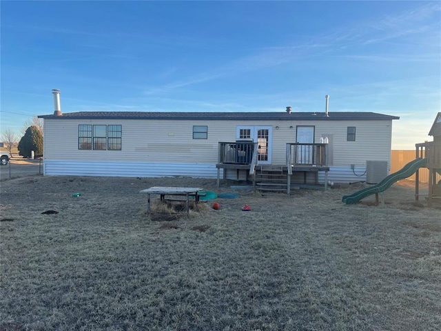 rear view of house with central air condition unit, a playground, and a wooden deck