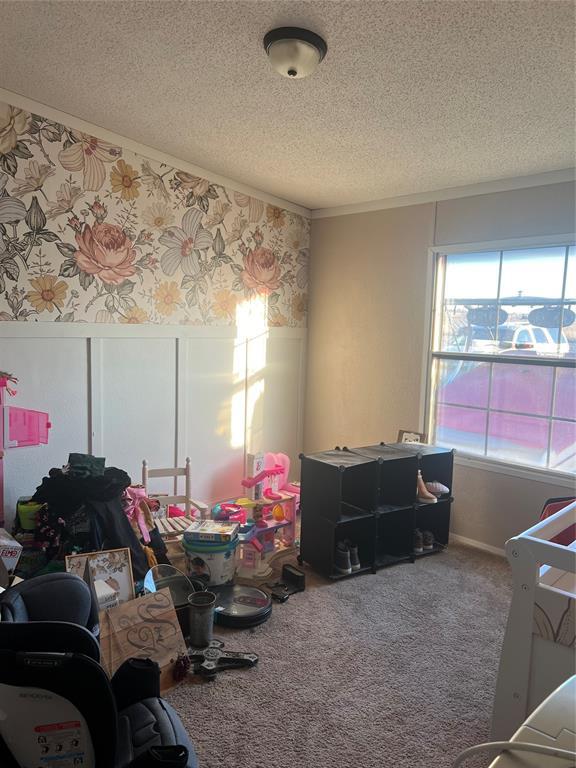 interior space featuring wainscoting, a textured ceiling, carpet flooring, and wallpapered walls