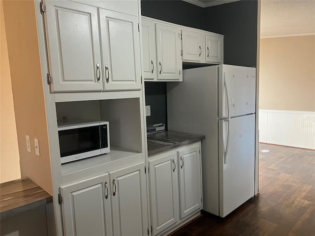 kitchen featuring a wainscoted wall, freestanding refrigerator, dark wood-type flooring, and white cabinetry