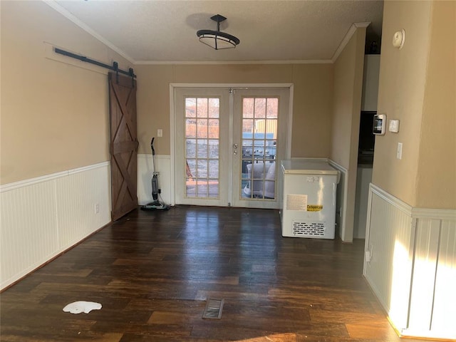 interior space featuring ornamental molding, a barn door, wainscoting, and wood finished floors