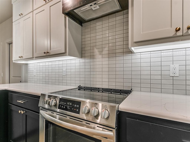 kitchen featuring stainless steel electric range oven, light stone counters, decorative backsplash, and under cabinet range hood