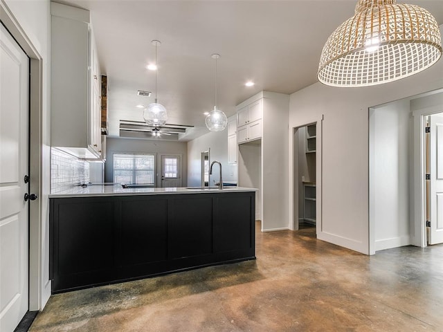 kitchen with a peninsula, visible vents, baseboards, finished concrete flooring, and tasteful backsplash