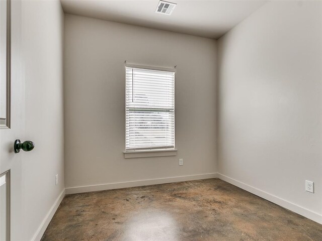 spare room featuring baseboards, visible vents, and unfinished concrete floors