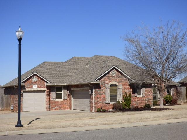 ranch-style house featuring an attached garage, a shingled roof, concrete driveway, and brick siding