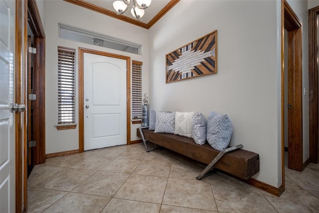 foyer entrance with light tile patterned floors, ornamental molding, an inviting chandelier, and baseboards