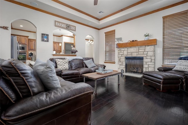 living room with crown molding, visible vents, a fireplace, and hardwood / wood-style flooring