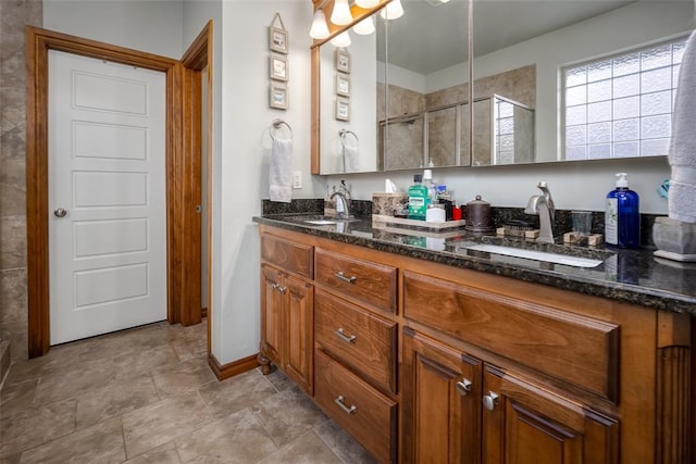 full bath featuring baseboards, double vanity, a sink, and a shower stall