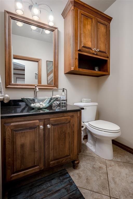 bathroom with tile patterned flooring, baseboards, vanity, and toilet