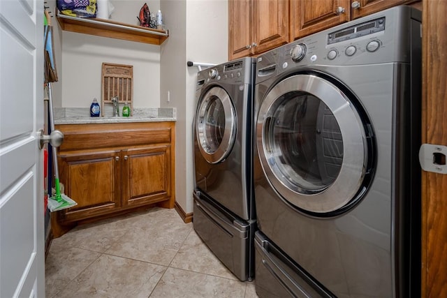 clothes washing area with washing machine and dryer, cabinet space, a sink, and light tile patterned floors