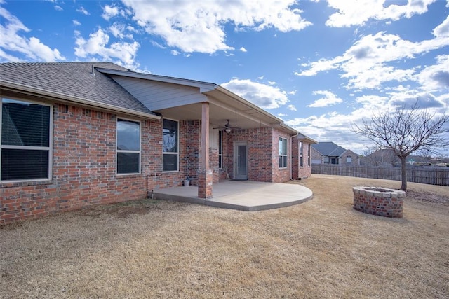 rear view of house featuring brick siding, roof with shingles, a patio area, fence, and a fire pit