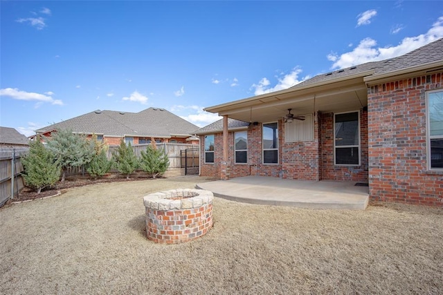 back of house featuring a fire pit, a ceiling fan, a patio, a fenced backyard, and brick siding