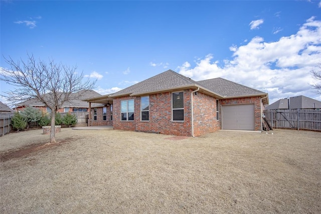 view of front facade featuring driveway, a shingled roof, a fenced backyard, an attached garage, and brick siding