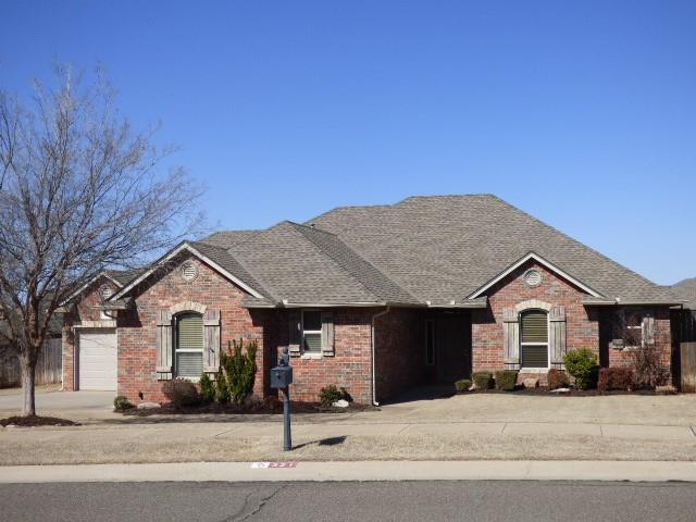 ranch-style home with driveway, brick siding, an attached garage, and a shingled roof