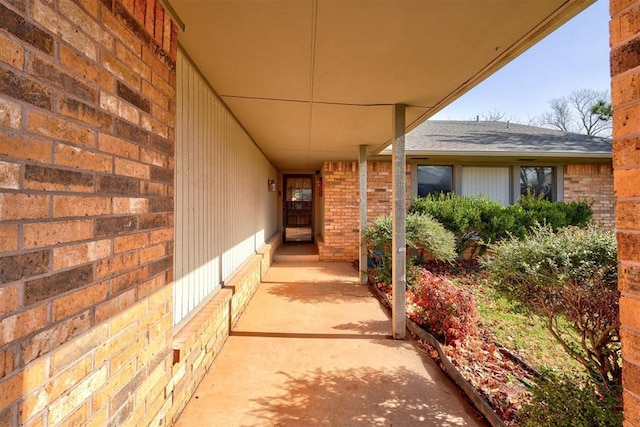 entrance to property with brick siding and a shingled roof