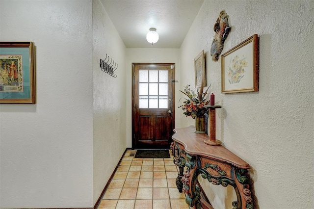 doorway to outside with light tile patterned floors and a textured wall