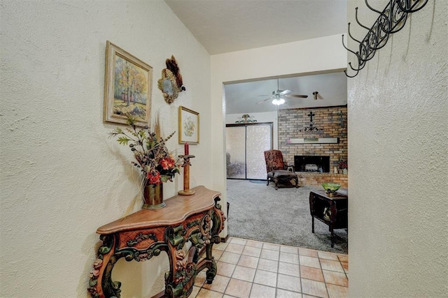 hall featuring light tile patterned floors, vaulted ceiling, light colored carpet, and a textured wall