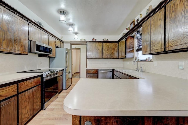 kitchen featuring a sink, stainless steel appliances, a peninsula, and light countertops