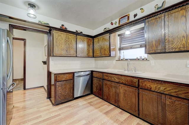 kitchen featuring a sink, light countertops, light wood-style flooring, and stainless steel appliances