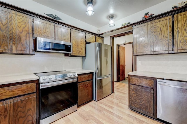 kitchen with stainless steel appliances, light countertops, and light wood-style floors