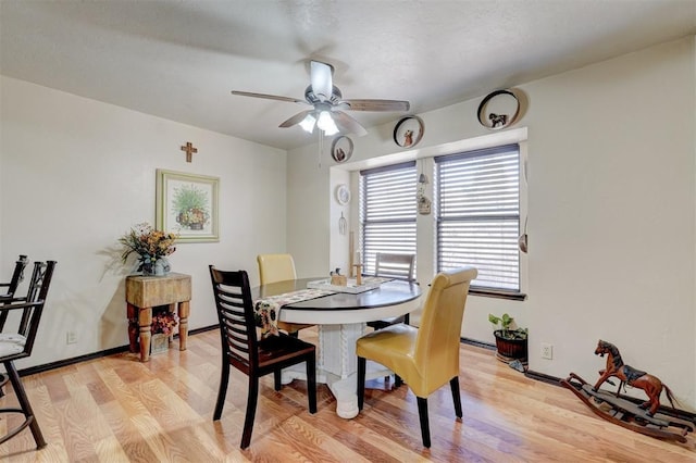 dining room featuring baseboards, light wood-style floors, and a ceiling fan