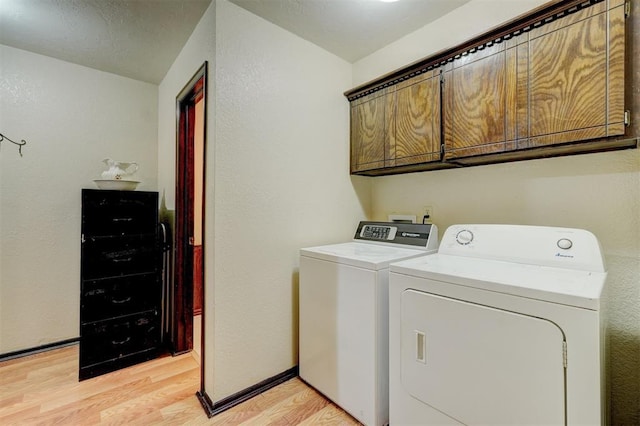 laundry area with cabinet space, separate washer and dryer, light wood finished floors, baseboards, and a textured wall