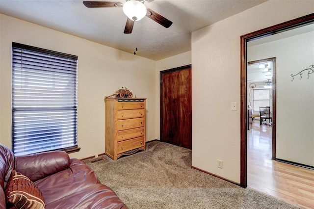 interior space with a wealth of natural light, baseboards, light colored carpet, and a ceiling fan