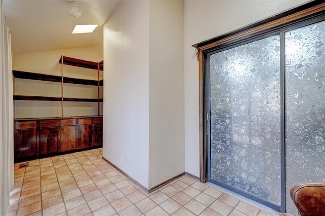 interior space with lofted ceiling, light tile patterned flooring, and baseboards