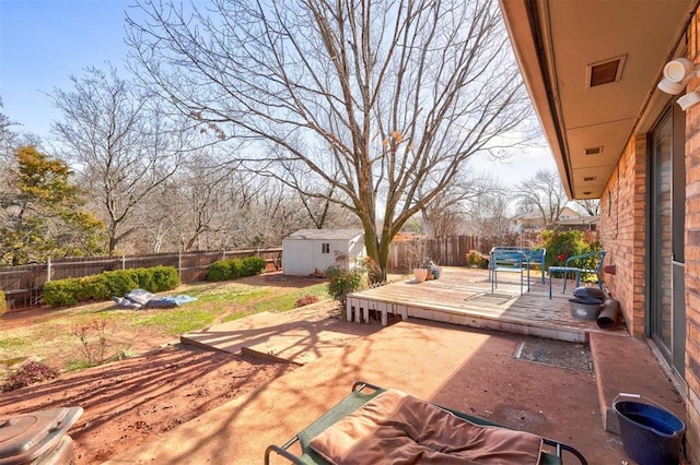 view of patio featuring a wooden deck, an outbuilding, a fenced backyard, and a shed