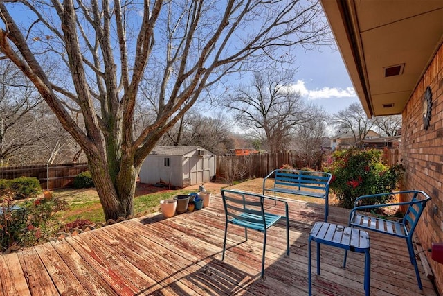 deck featuring a storage unit, a fenced backyard, and an outdoor structure