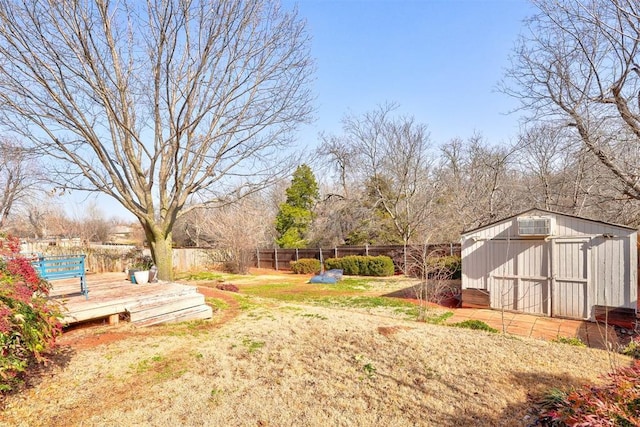 view of yard with a deck, an outdoor structure, a fenced backyard, and a shed