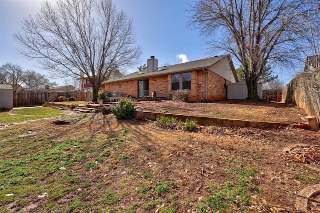 view of front facade with brick siding, an outdoor structure, a chimney, and fence