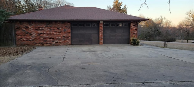 garage at dusk with concrete driveway