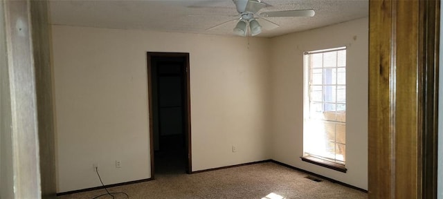 empty room with carpet, visible vents, a ceiling fan, a textured ceiling, and baseboards