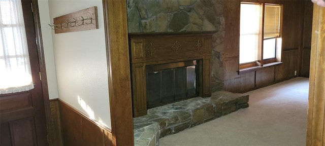 living room featuring carpet, wainscoting, a fireplace, and wooden walls