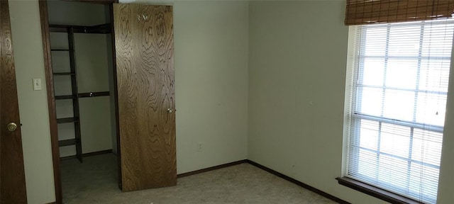 unfurnished room featuring light colored carpet and baseboards