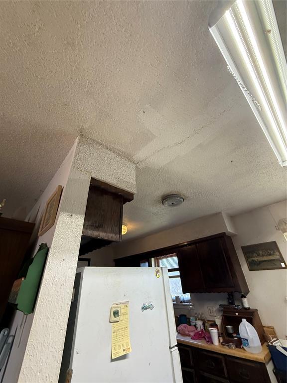 interior details featuring freestanding refrigerator and a textured ceiling