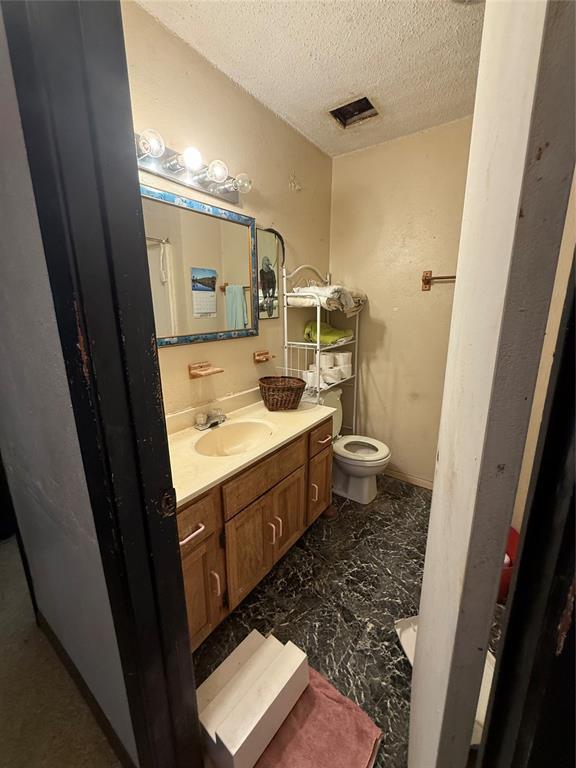 bathroom featuring marble finish floor, visible vents, toilet, a textured ceiling, and vanity