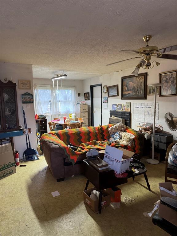 living room featuring ceiling fan and a textured ceiling