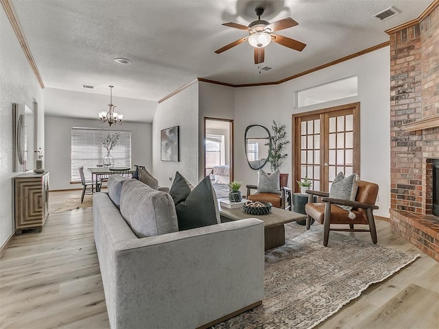 living room featuring visible vents, light wood-style flooring, ornamental molding, a brick fireplace, and a textured ceiling