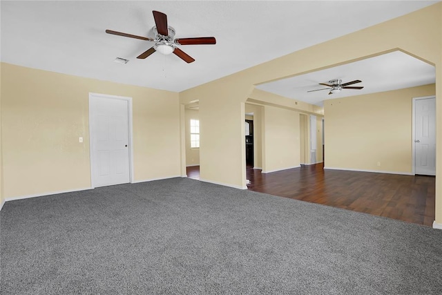 unfurnished room featuring visible vents, dark carpet, and ceiling fan