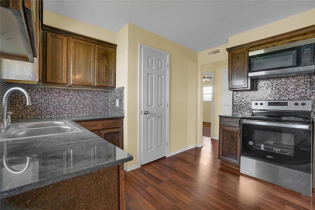 kitchen with visible vents, dark wood-type flooring, a sink, stainless steel appliances, and backsplash