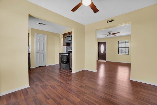 unfurnished living room with visible vents, dark wood finished floors, baseboards, and ceiling fan