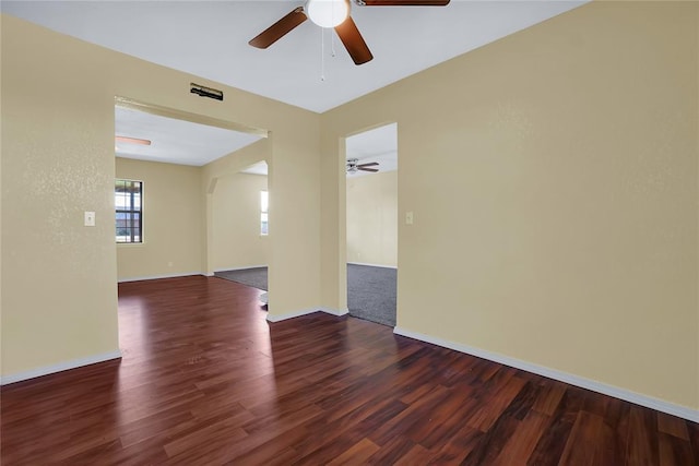 spare room featuring dark wood-style floors, ceiling fan, and baseboards