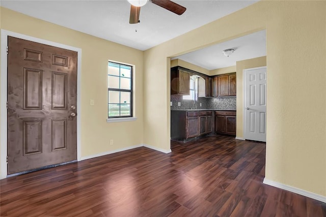 kitchen featuring dark brown cabinetry, tasteful backsplash, baseboards, dark wood finished floors, and a sink