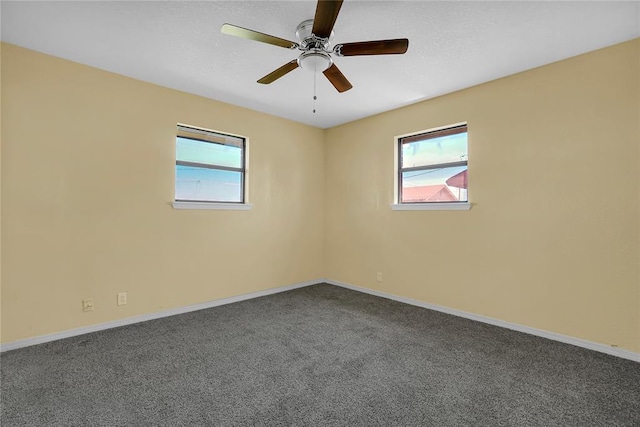 empty room featuring ceiling fan, dark colored carpet, and baseboards